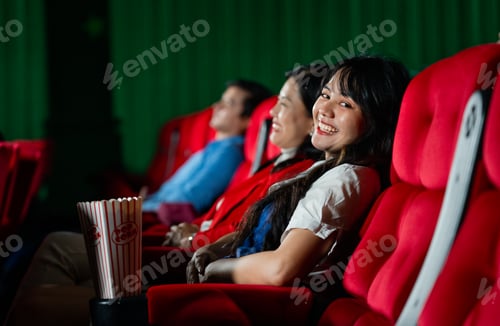 Preview: Asian young adult woman sit on cinema seat with her sister and look at camera with smiling