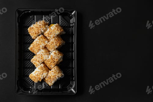 Preview: Sushi rolls in a package on a black background, top view.