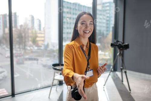 Preview: Dark-haired young cute reporter with camera smiling positively