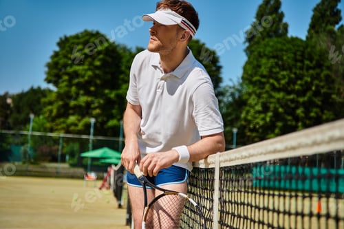 Preview: Handsome man enjoys summer tennis on the court in crisp white sportswear