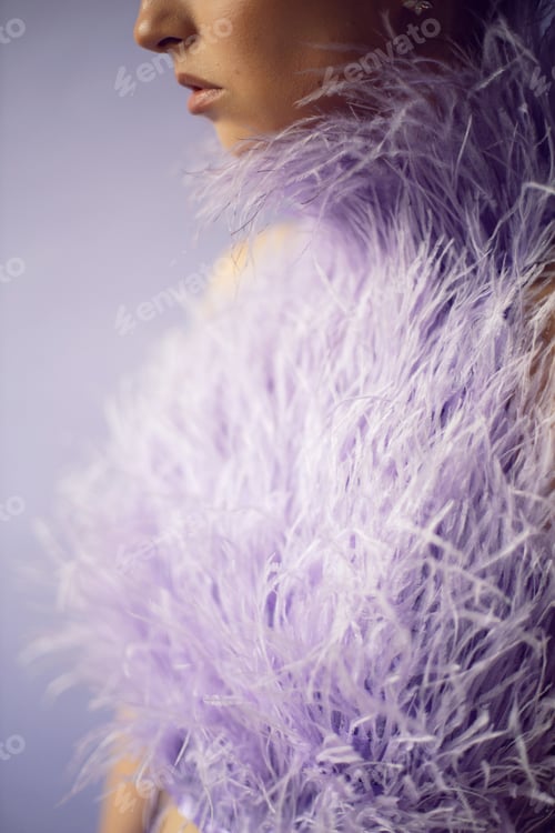 Preview: Portrait of a woman in an evening purple dress with feathers and make-up in the studio on the backgr