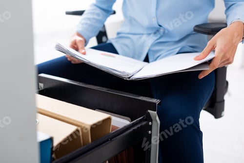 Preview: Cropped view of businesswoman holding folder with papers near open cabinet driver on white