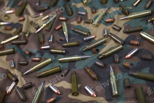Preview: Many rifle bullets and cartridges on dark camouflage background