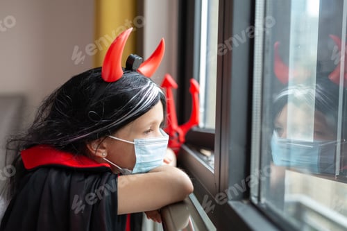 Preview: Sad little girl in evil costume celebrating Halloween alone during coronavirus covid-19 pandemic