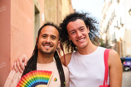 Preview: Two homosexual men are smiling and holding a rainbow fan during Pride Parade.
