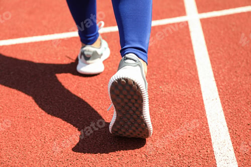 Preview: Girl walking on red athletic track, close up