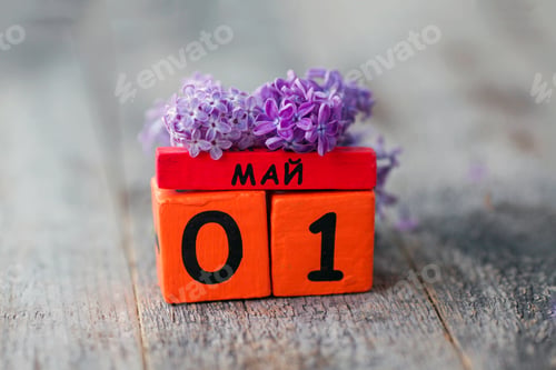 Preview: Wooden calendar with Russian text May 1 and a bouquet of lilacs on a wooden background.