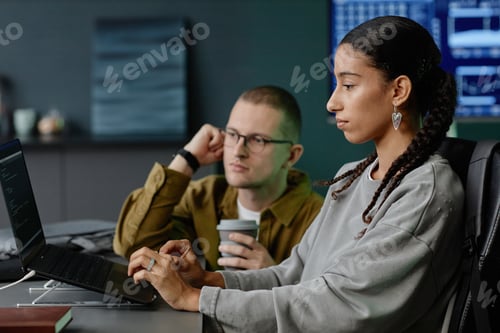 Preview: Focused Female Trainee Typing on Laptop with Male Colleague Assisting at Meeting In Office