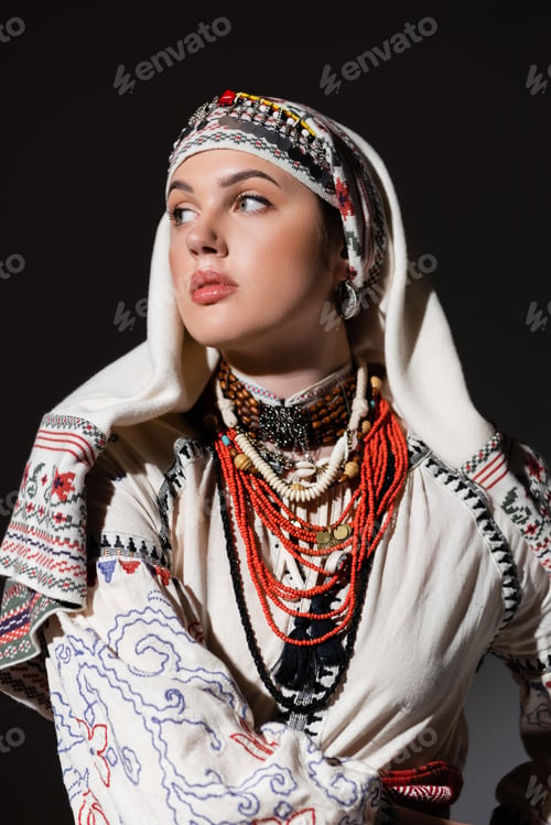Preview: brunette ukrainian woman in traditional shirt with ornament and red beads posing isolated on black