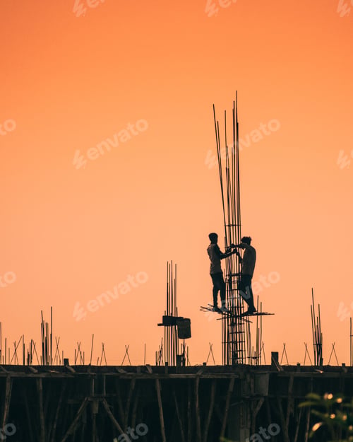 Preview: Closeup of construction workers working at the top of the building at sunset