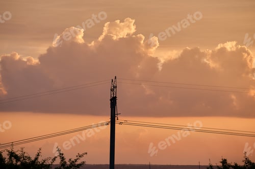 Preview: Dark silhouette of high voltage towers with electric power lines at sunrise