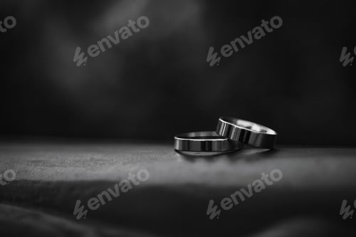 Preview: Two metal wedding rings on dark fabric surface with black background