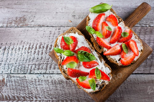 Preview: Top view of Strawberry bruschetta with cottage cheese,basil and strawberry on wooden board