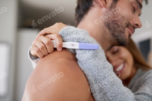 Preview: Shot of a happy young couple hugging after taking a pregnancy test at home