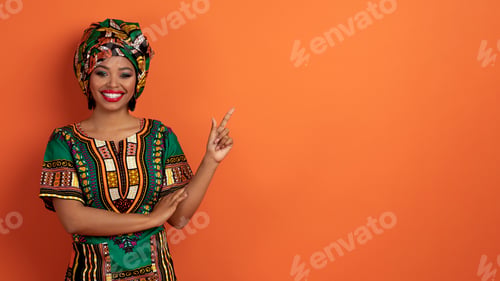 Preview: Cheery young black woman in african costume showing nice offer