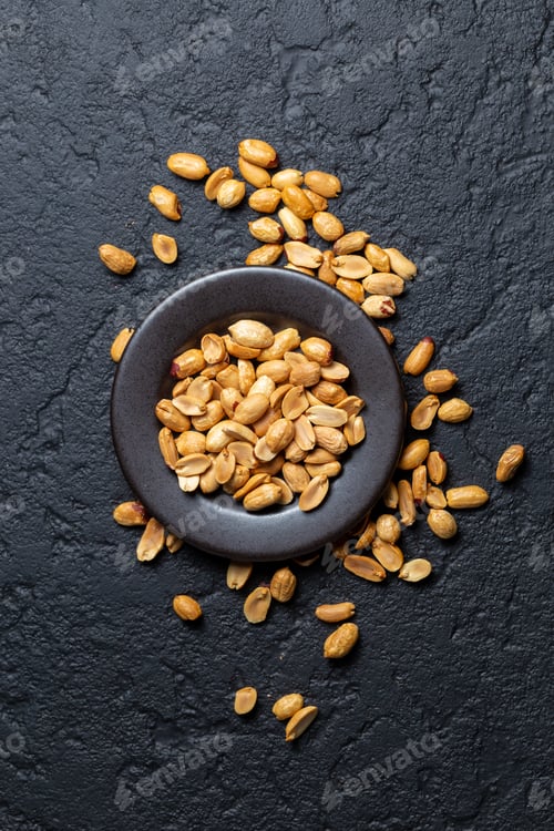 Preview: Pile of roasted peanuts on black background, space for text