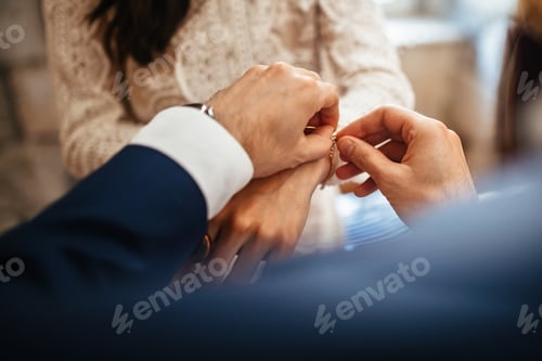 Preview: Close up of bride receiving bracelet from groom on their wedding day.