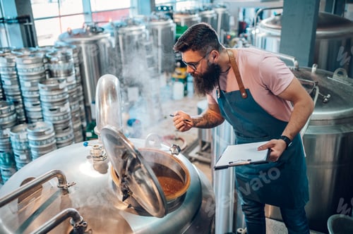 Preview: Man working in brewery and taking notes of the beer production