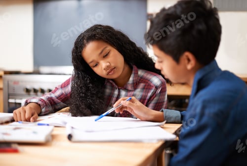Preview: Solving their homework together. Shot of two young students studying together in a classroom.