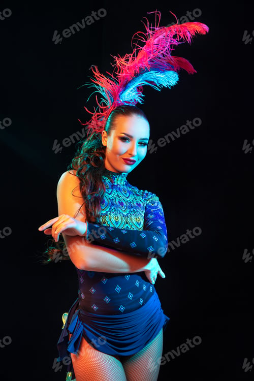 Preview: Beautiful young woman in carnival and masquerade costume in colorful neon lights on black background