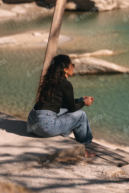 Preview: Young woman relaxing by the lake enjoying the scenic view