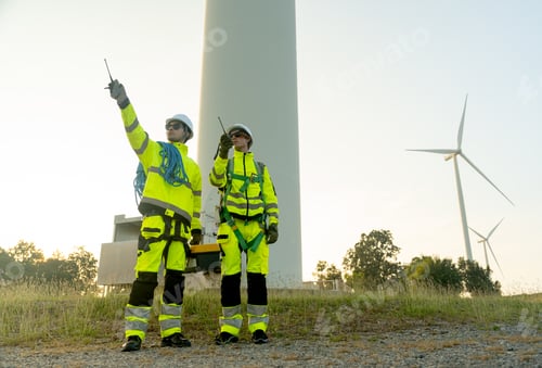 Preview: Wide shot of two of wind turbine or windmill workers or technician stand on base of wind turbine