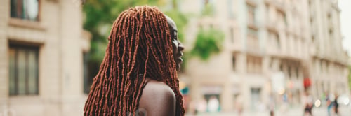 Preview: Woman with African braids wearing top crosses the road at crosswalk, Panorama