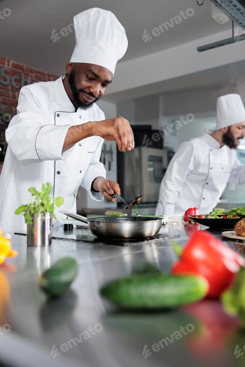 Preview: Food industry worker seasoning gourmet dish prepared for dinner service at fine dining restaurant.