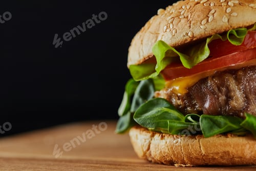 Preview: close up of delicious meat burger with cheese, greenery and sesame isolated on black