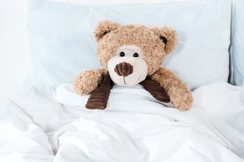 Preview: soft toy in bed with white bedding and pillows