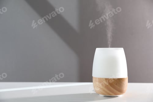 Preview: Modern aroma lamp on white wooden table against gray background. Space for text