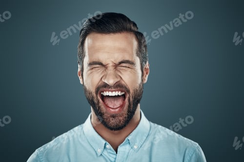 Preview: So much fun!. Handsome young man laughing while standing against grey background