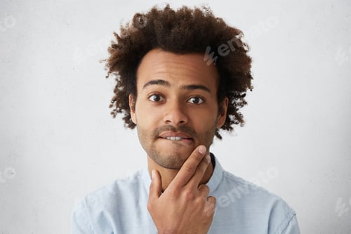 Preview: Headshot of handsome troubled or puzzled young African American man with funky hairstyle and stubble