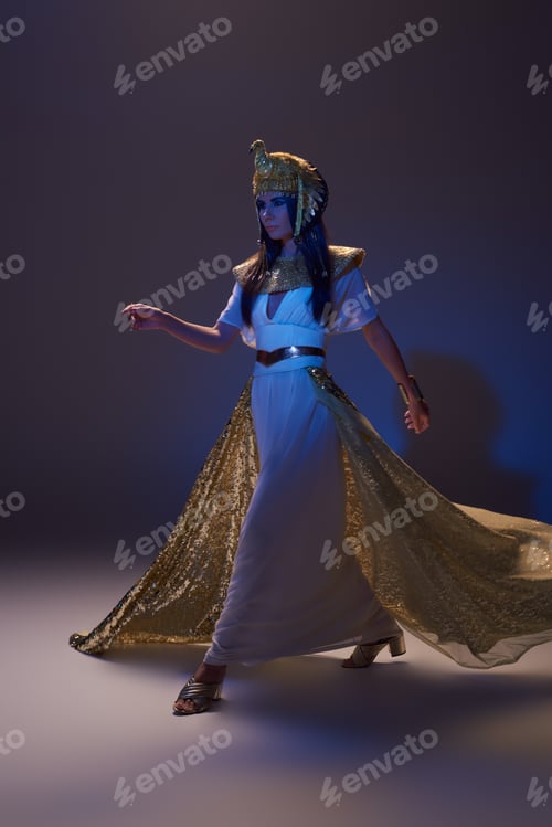 Preview: Full length of woman in egyptian look and headdress walking on brown background with blue light