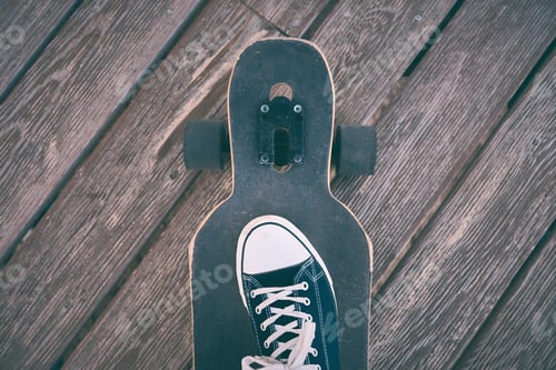 Preview: Feet of man in sneakers on a longboard at the evening