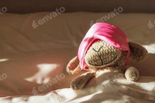 Preview: Knitted Sheep Toy Sleeping with Satin Mask on Cozy Bed under Morning Sunlight
