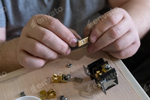 Preview: Male hands holding electrical outlet detail close-up. A repairman fixes a broken part