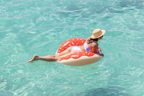 Preview: Beautiful woman with inflatable donut in sea