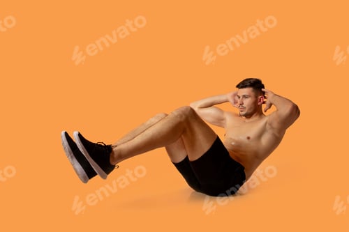 Preview: Fit Young Man Performing Crunches Against Orange Background in Studio