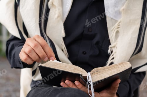 Preview: Close-up of Jewish man wearing tallit reading the siddur on Shabbat.