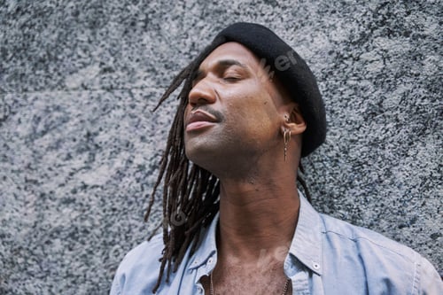Preview: handsome African-American man in braids with stylish beret looking away
