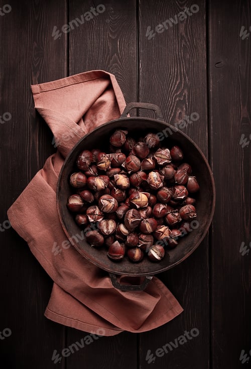 Preview: Roasted chestnuts, in an iron pan, wooden table, top view, no people, rustic style,