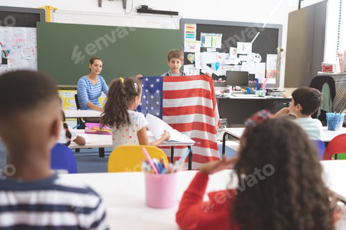 Preview: Schoolboy holding american flag in classroom at school
