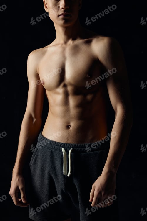 Preview: male bodybuilder in gray pants naked torso pumped up muscles black background
