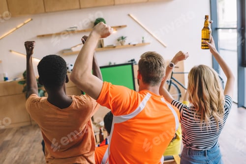 Preview: high angle view of group of friends celebrating and doing yes gestures while watching soccer match