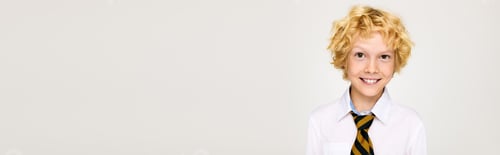 Preview: Blonde boy with wavy hair smiles in a school uniform during studio session
