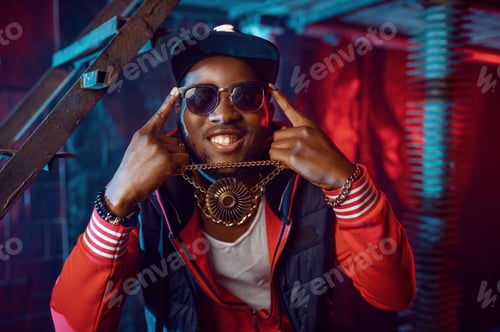 Preview: Smiling rapper with gold chain posing in studio
