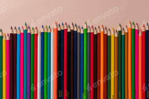 Preview: a row of set of colored pencils flat lay on pastel background