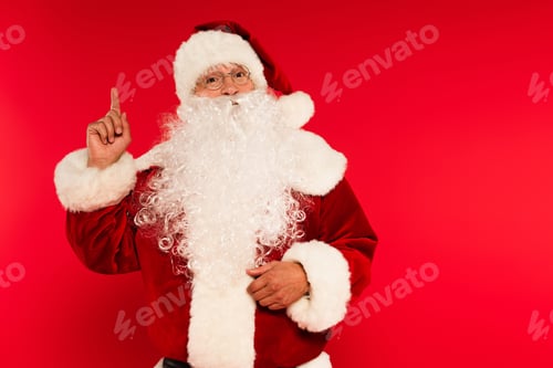 Preview: Bearded santa claus in eyeglasses having idea on red background