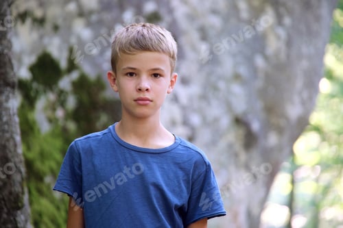 Preview: Portrait of handsome teenager boy in casual clothes smiling in camera on green sunny background